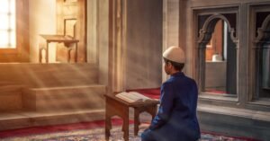 A young boy kneels in prayer inside a mosque with sunlight streaming through the window.